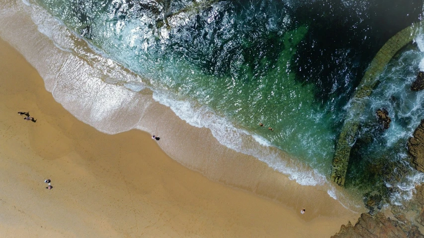 people walk on the beach along the edge of an ocean