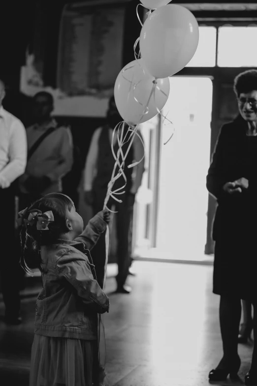 a young child holding up a balloon while another man looks on