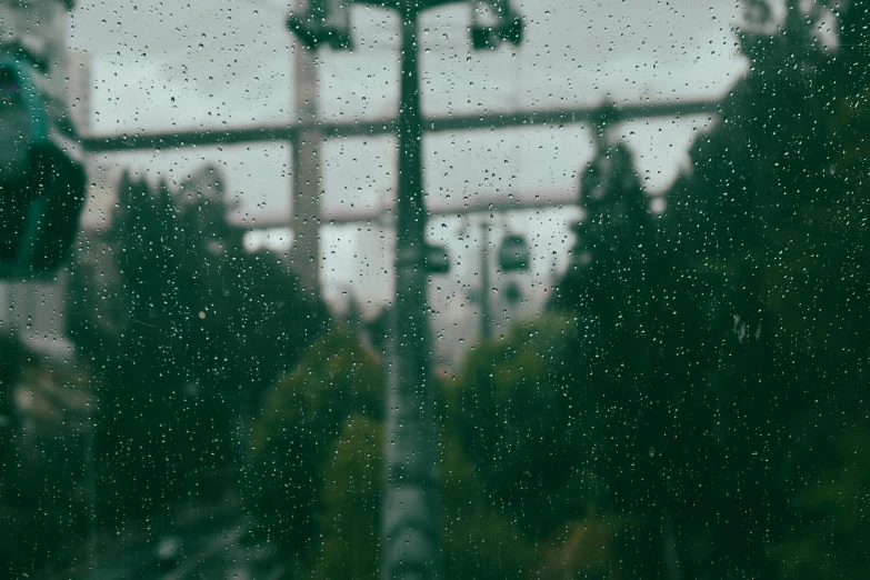 there is rain on a street light with trees