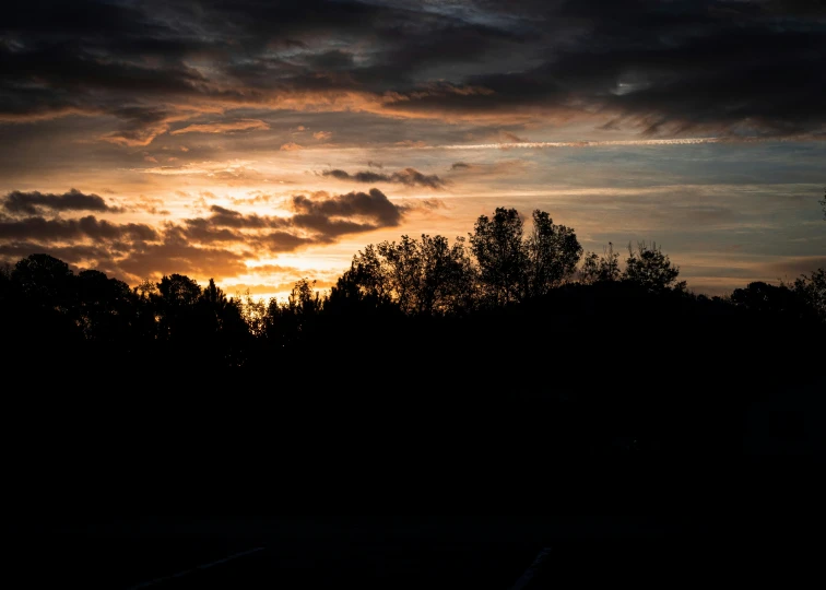 the sky is dark and cloudy, and you can see some clouds over the trees