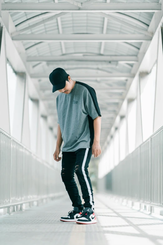 a man wearing a gray shirt and black pants on a skateboard