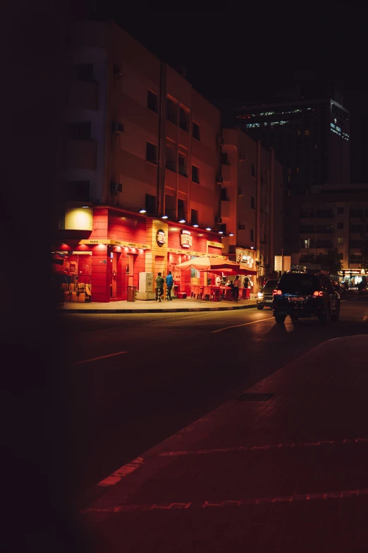 a busy city street at night in front of a restaurant