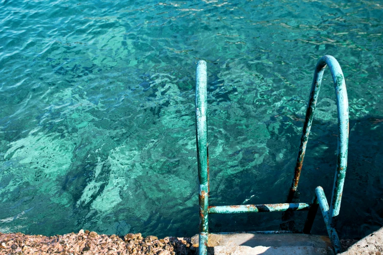 a rusty metal object with bright clear blue water