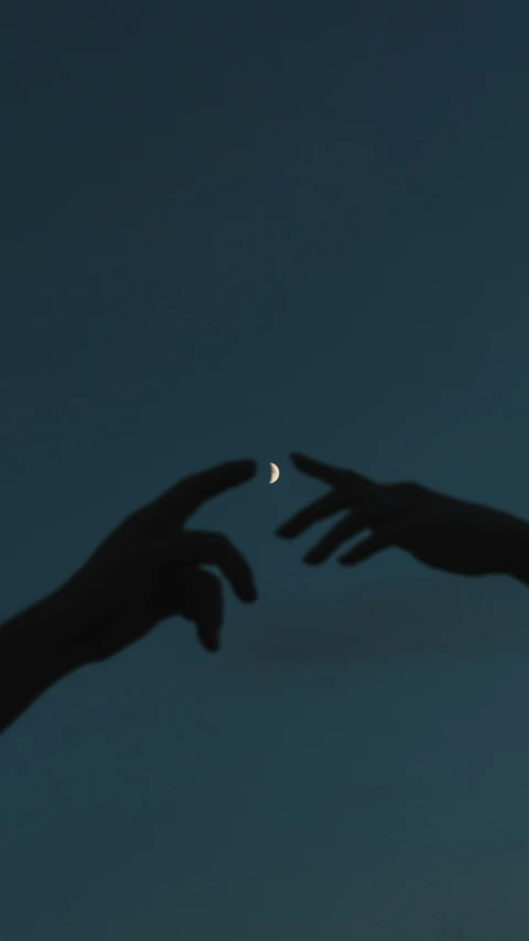 two hands reach out to reach the moon