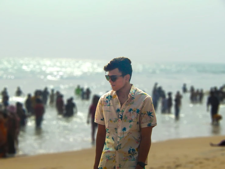 a man with sunglasses and a shirt stands on the beach