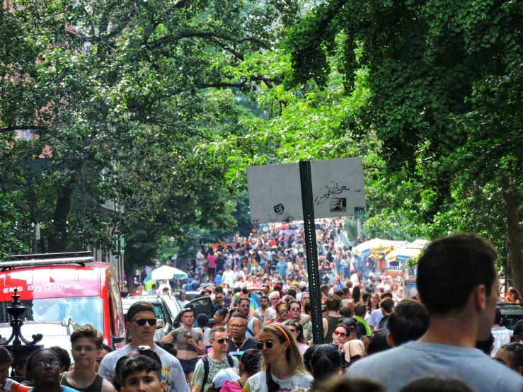 the large crowd is walking on the sidewalk near the trees