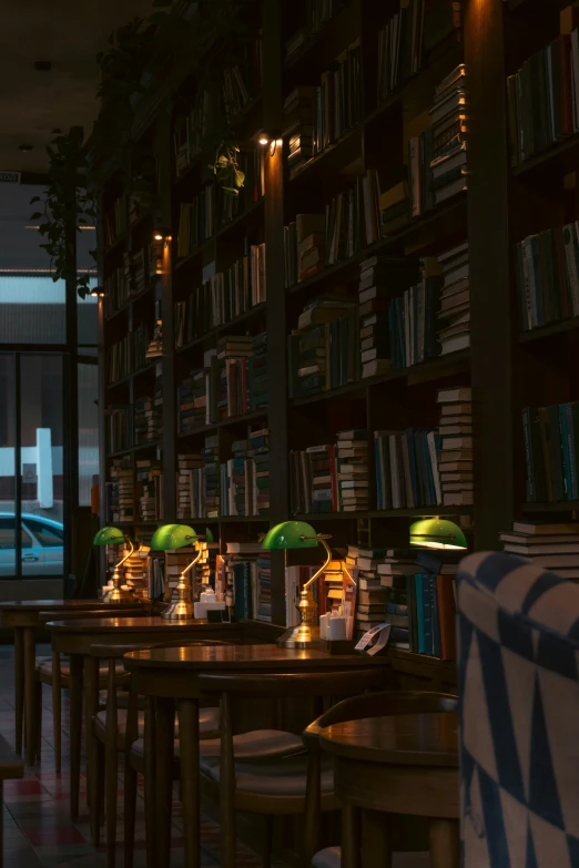 some tables with green umbrellas in front of a book shelf filled with books