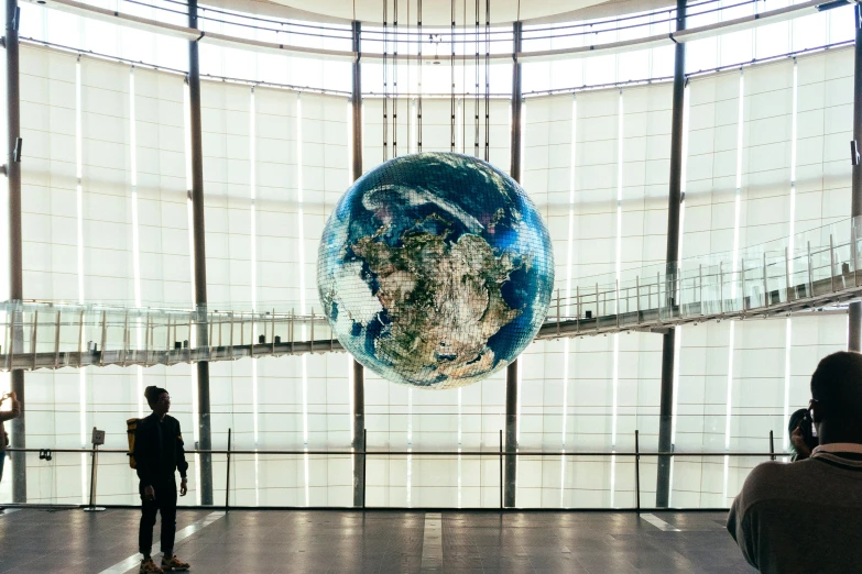 people standing in front of a globe shaped sculpture