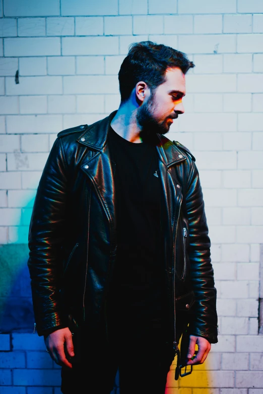 the young man is posing by a brick wall