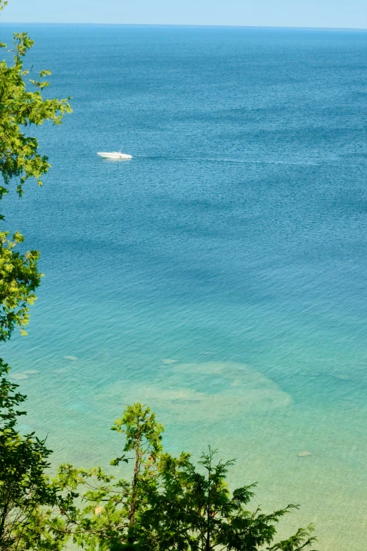 a lone boat sits in the blue ocean