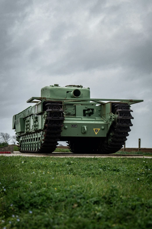 a military tank sits in the middle of a grassy area