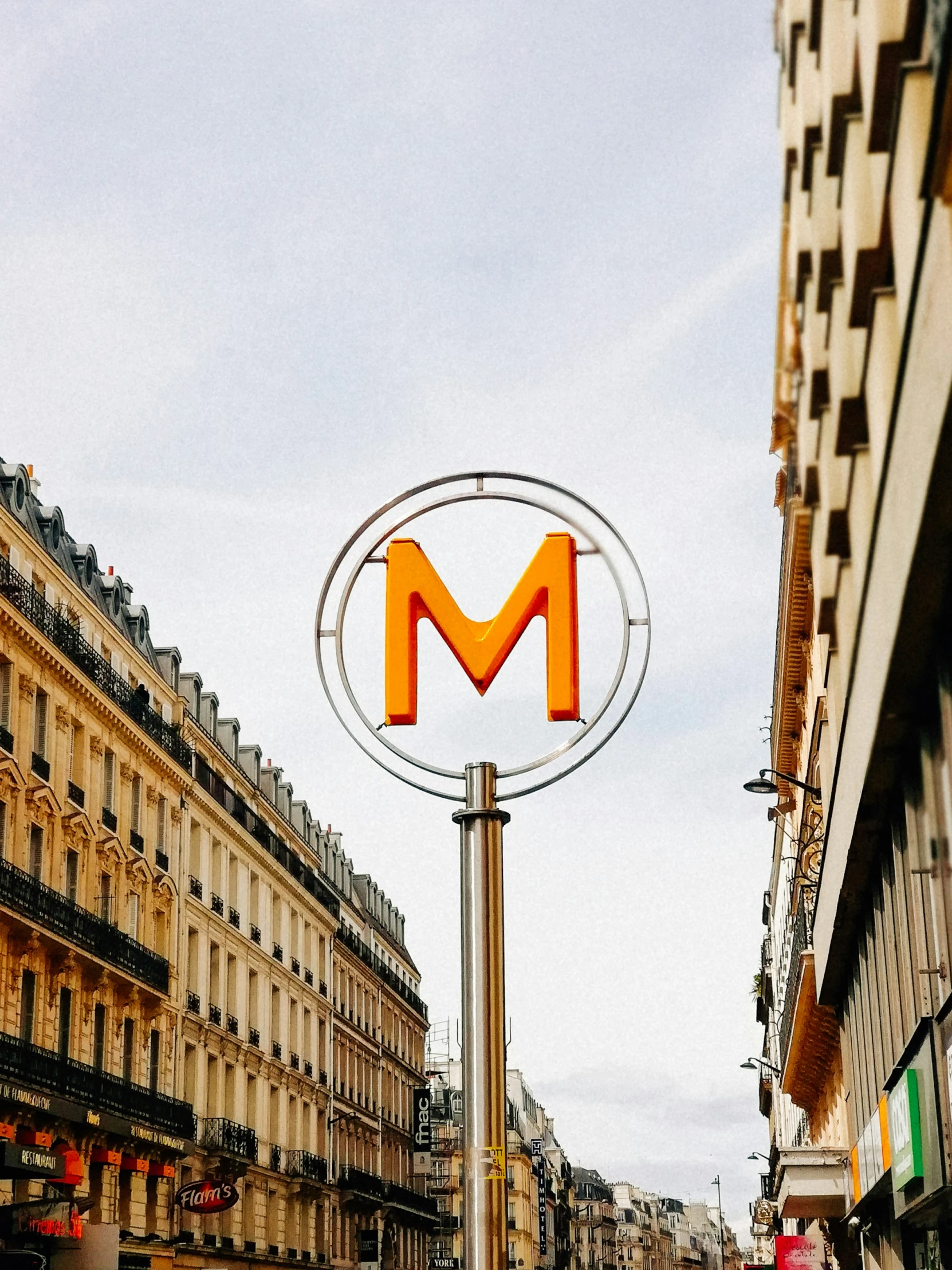 an orange letter m sitting on the side of a street