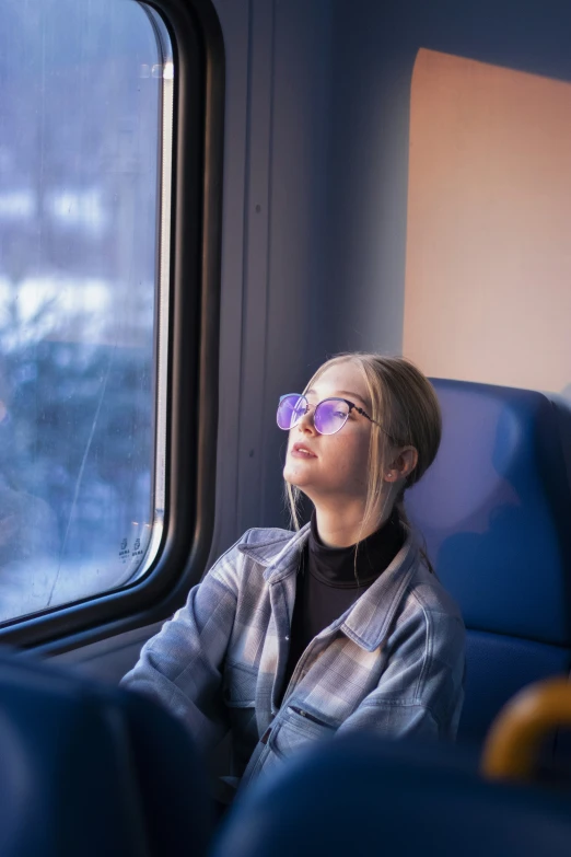 a woman wearing glasses sits on a train