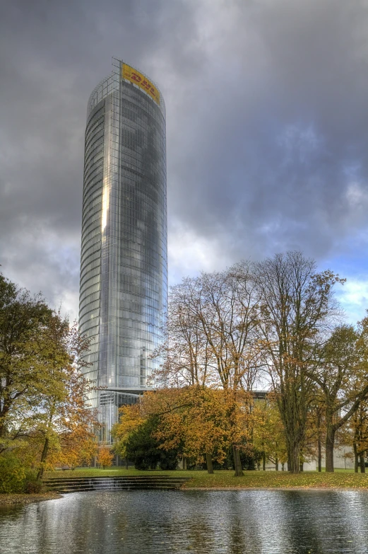 a tall glass skyscr is on the other side of a lake