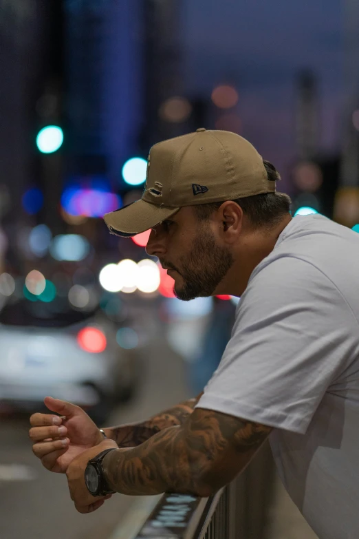 a man with tattoos sitting by a window in the city