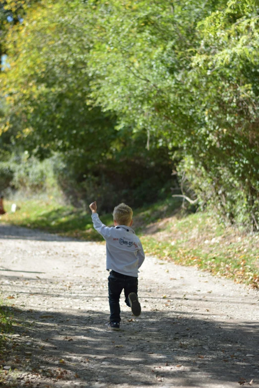 a child playing with a frisbee by a dirt road