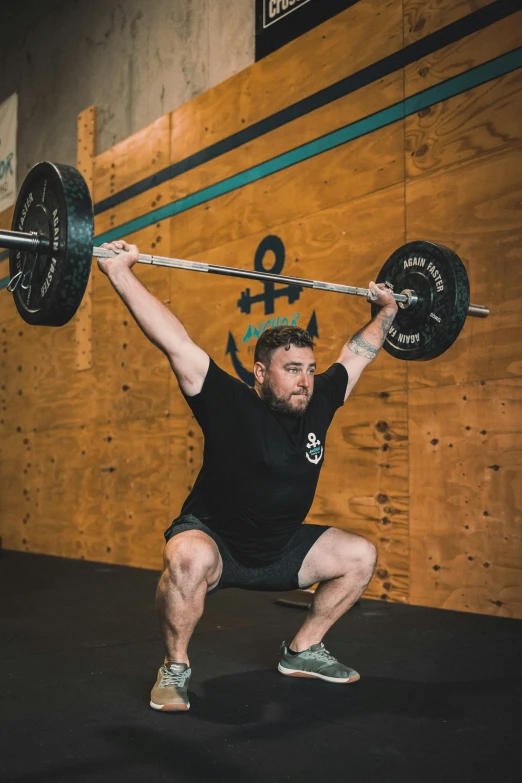 man doing a squat with a barbell in a cross - country event