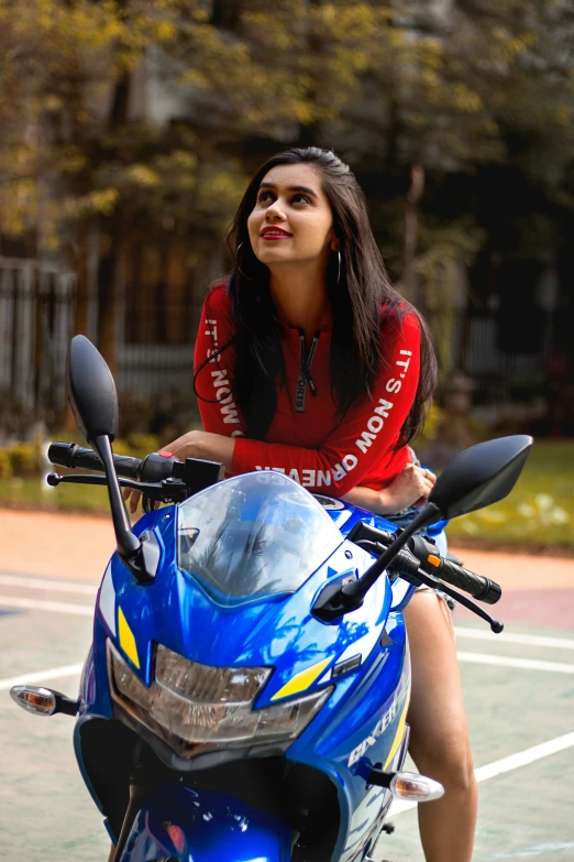 a woman in red shirt on blue motorcycle