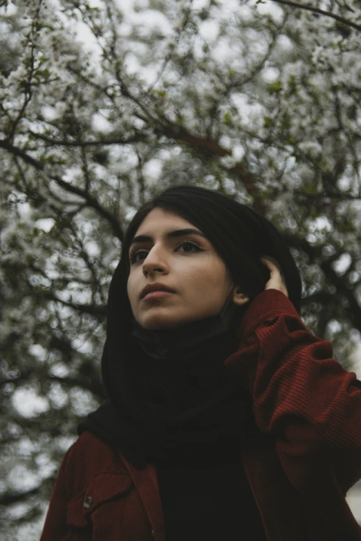 woman looking up in front of white flowered tree