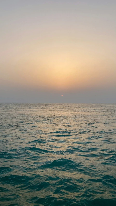 two boats floating in the ocean at sunset