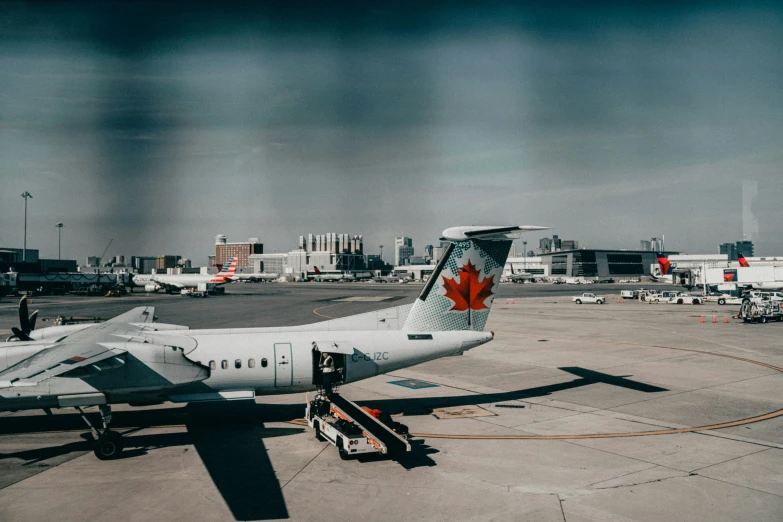 canadian plane at an airport with others and vehicles parked