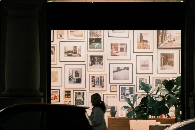 woman walking by picture frames on a wall