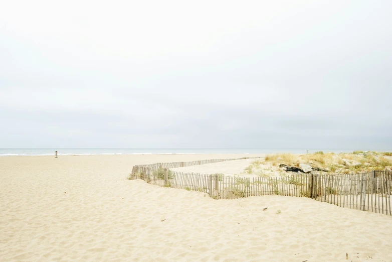 a person on the beach walking alone by some fence