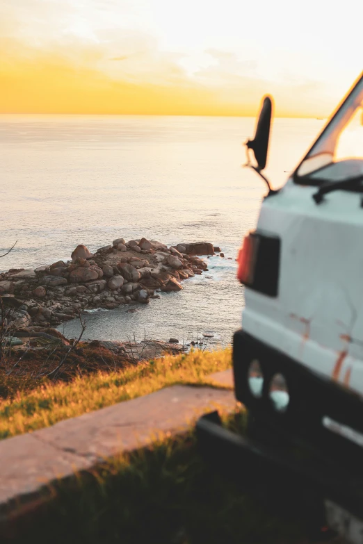 an old car is parked near a rock cliff by the ocean