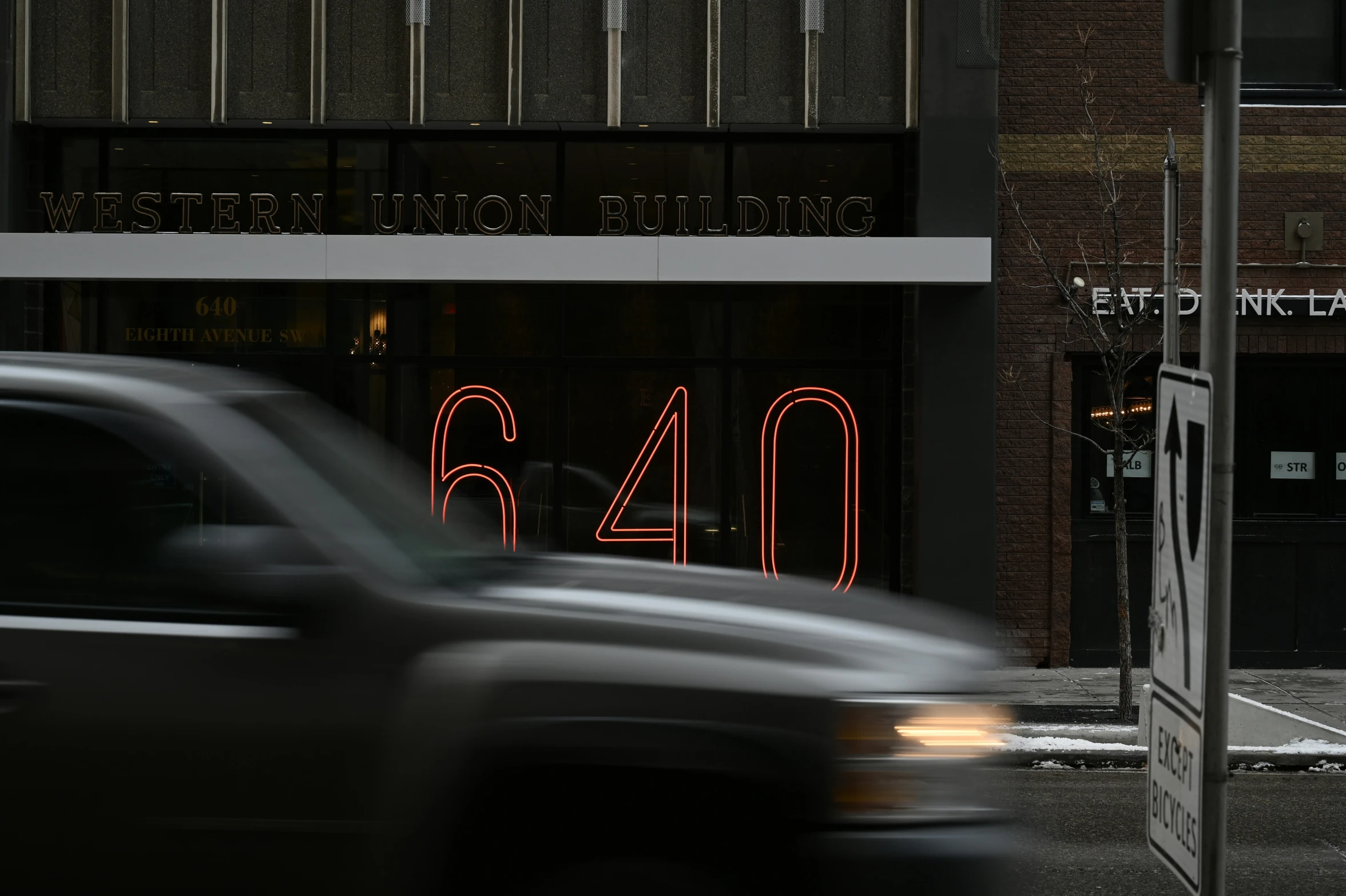 a car driving down the street by a business front