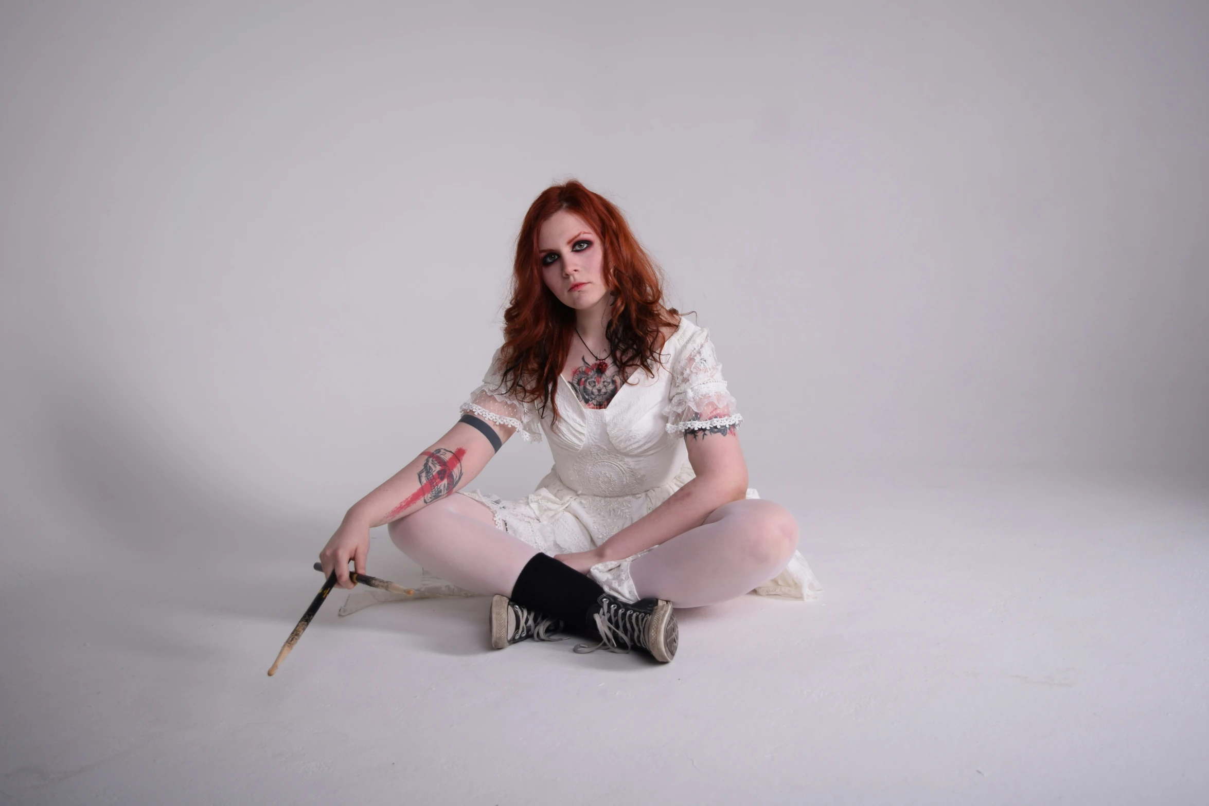 woman in white bodysuit kneeling and holding a sword