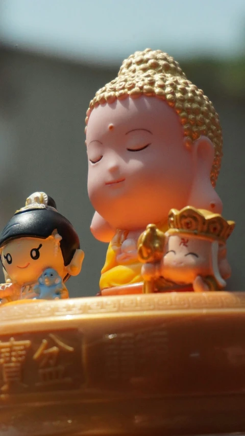 two figurines with a buddha in a yellow outfit and one with a doll