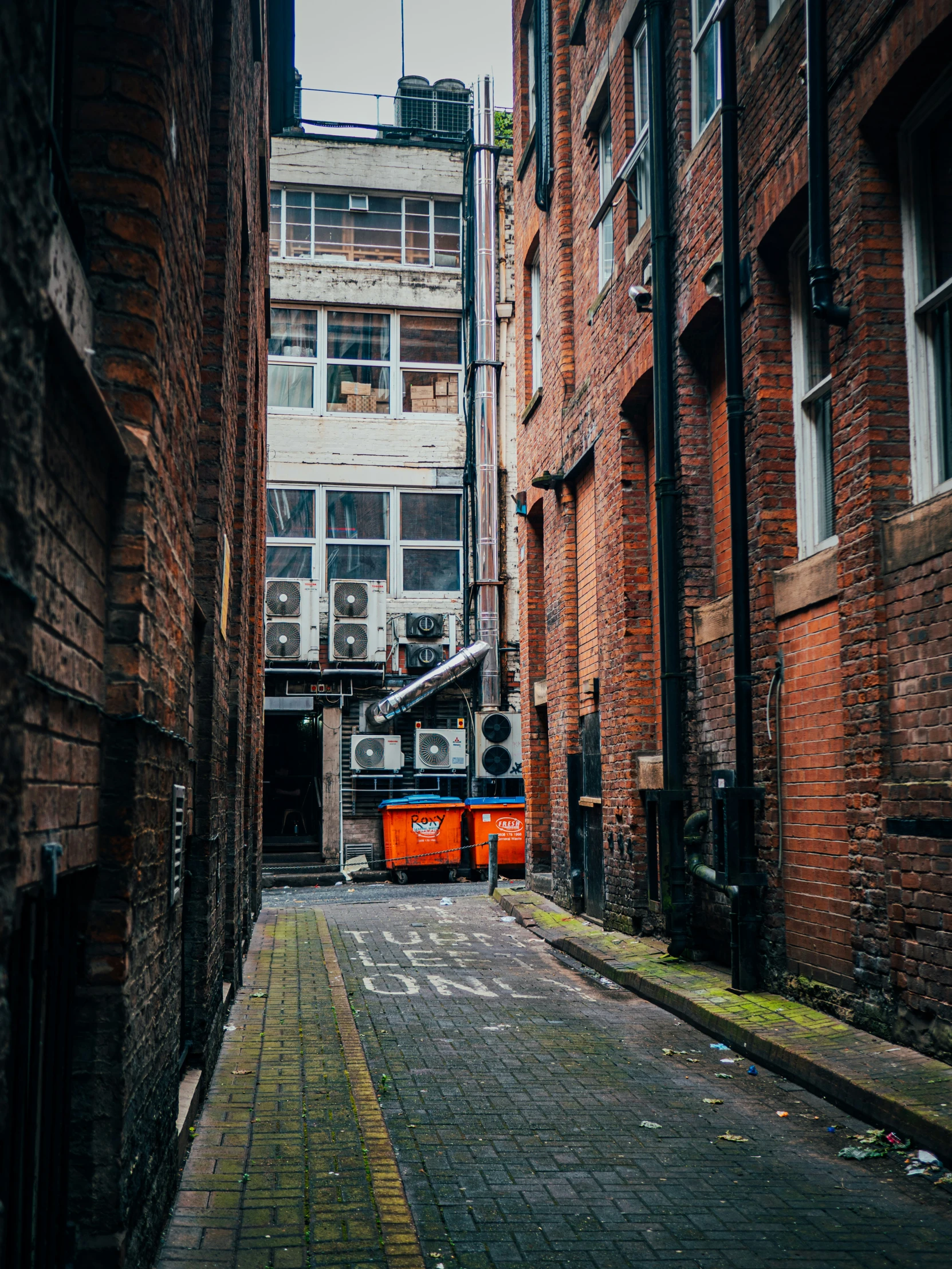 an alleyway with red graffiti and brick walls