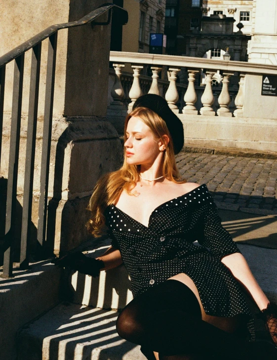 a woman in a dress sits on steps with her arms crossed