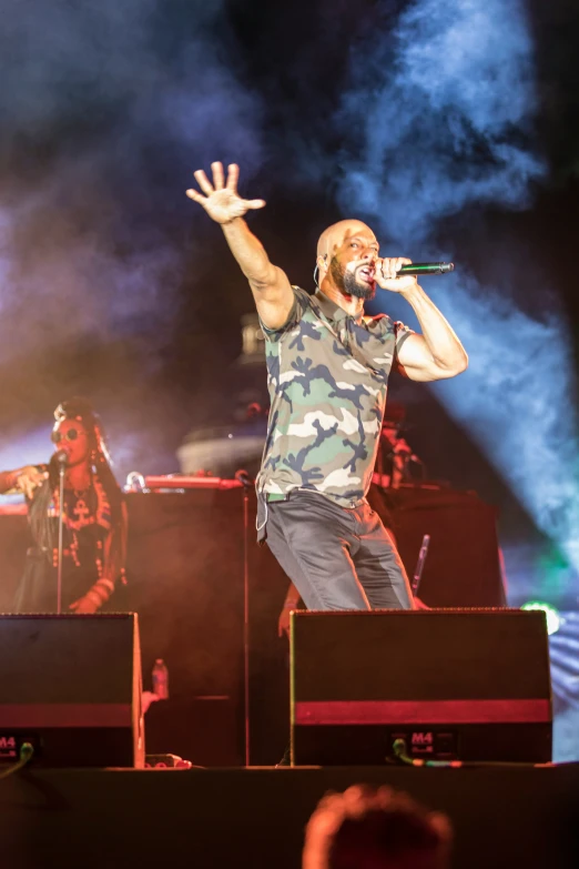 a man in a camo shirt and jeans on stage