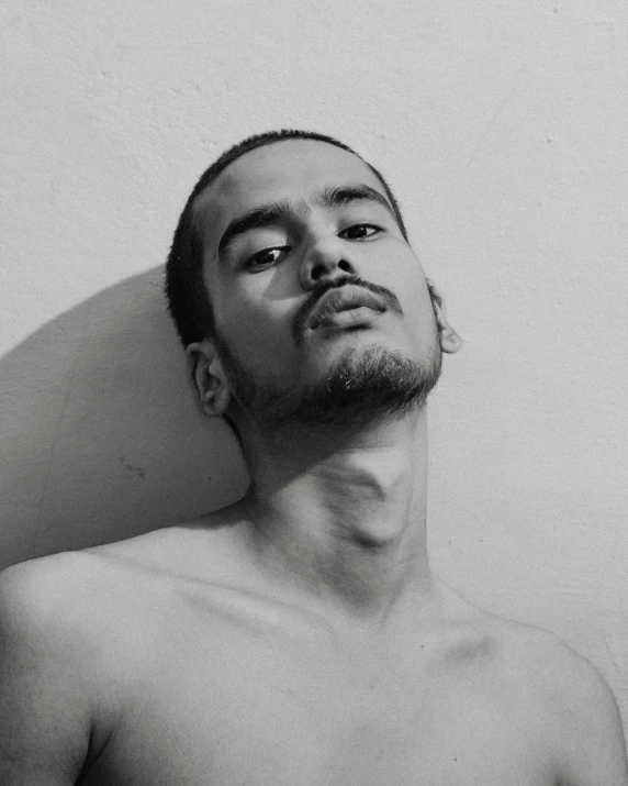 a shirtless man with his face propped up against the wall