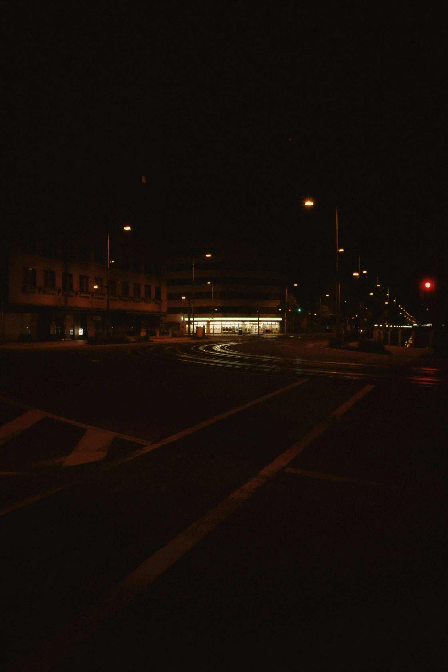 the city street lights and street signs reflect off of the wet asphalt