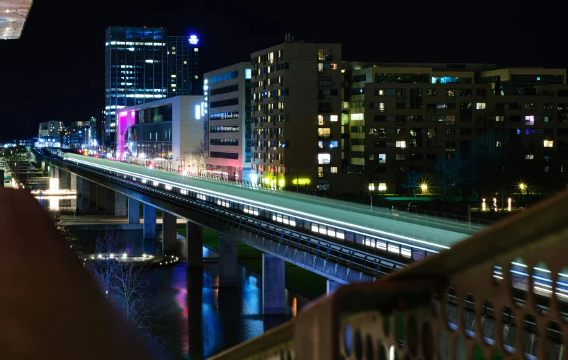 city lights shine on a bridge that runs over the river