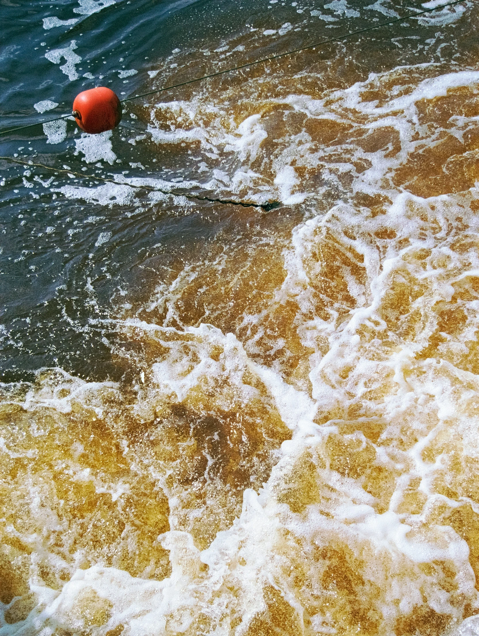 an orange buoy floating through a wave on top of the ocean