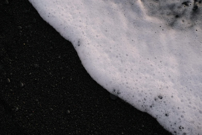 black sand and ice next to a beach