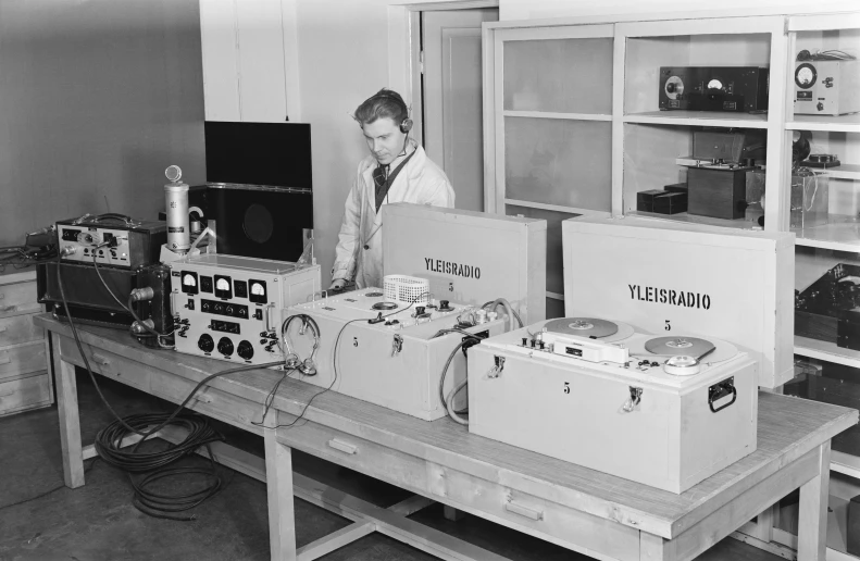 a man standing at a desk with boxes and electronic equipment