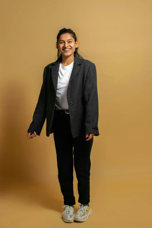 a smiling woman stands in front of a gold background