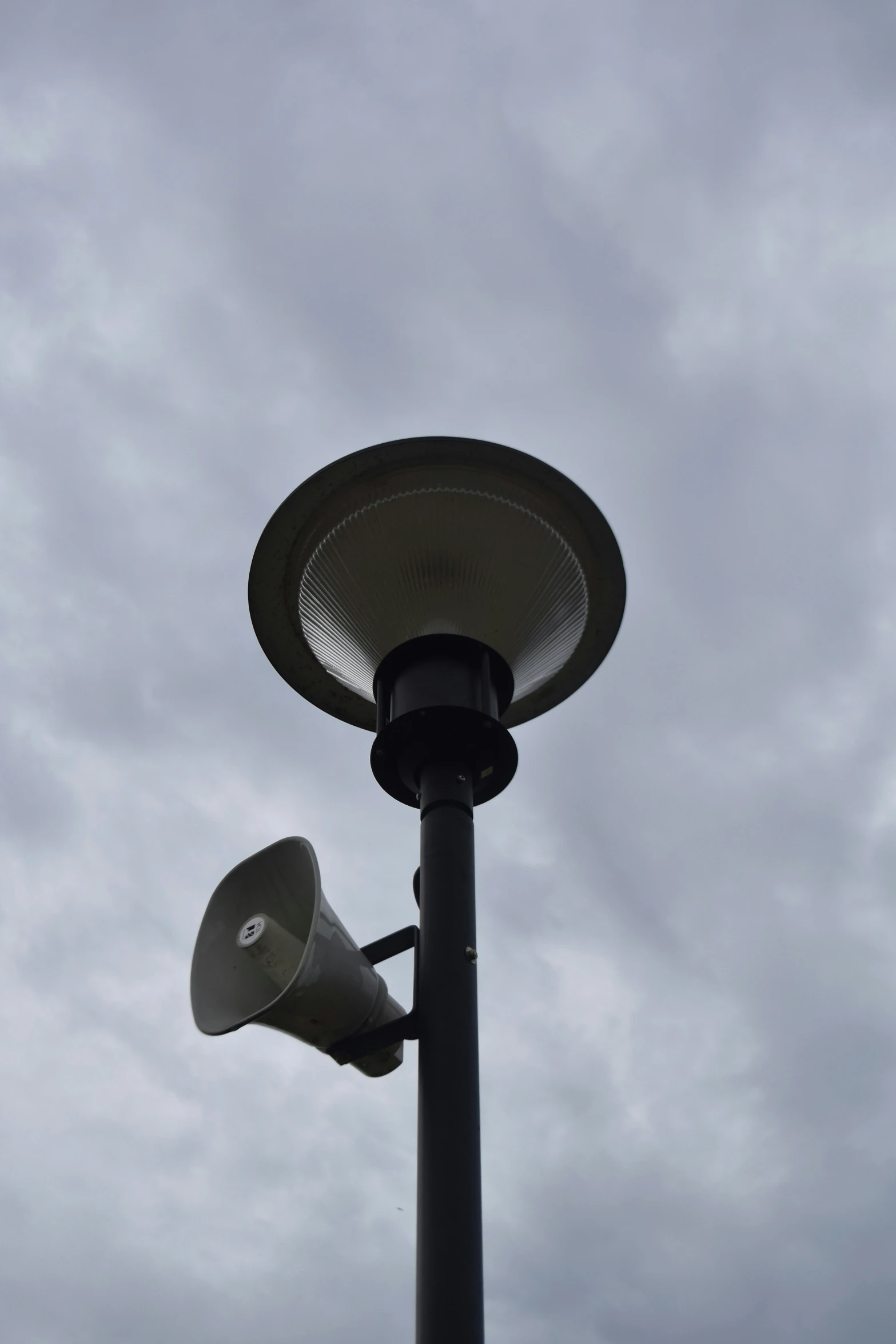 an outdoor lamp post with an empty cup hanging off of it