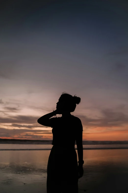 a woman walking on top of a beach next to the ocean