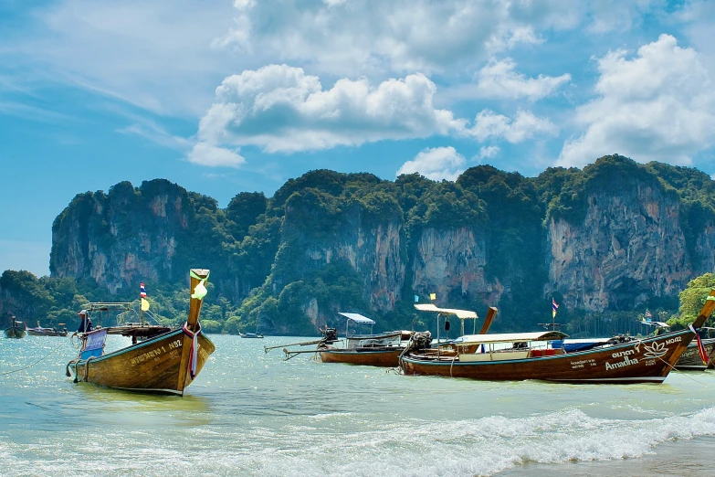 some very pretty boats in the water by a big mountain