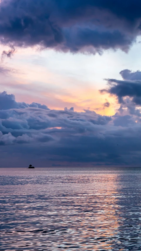 this po shows an ocean and clouds with a boat in the distance