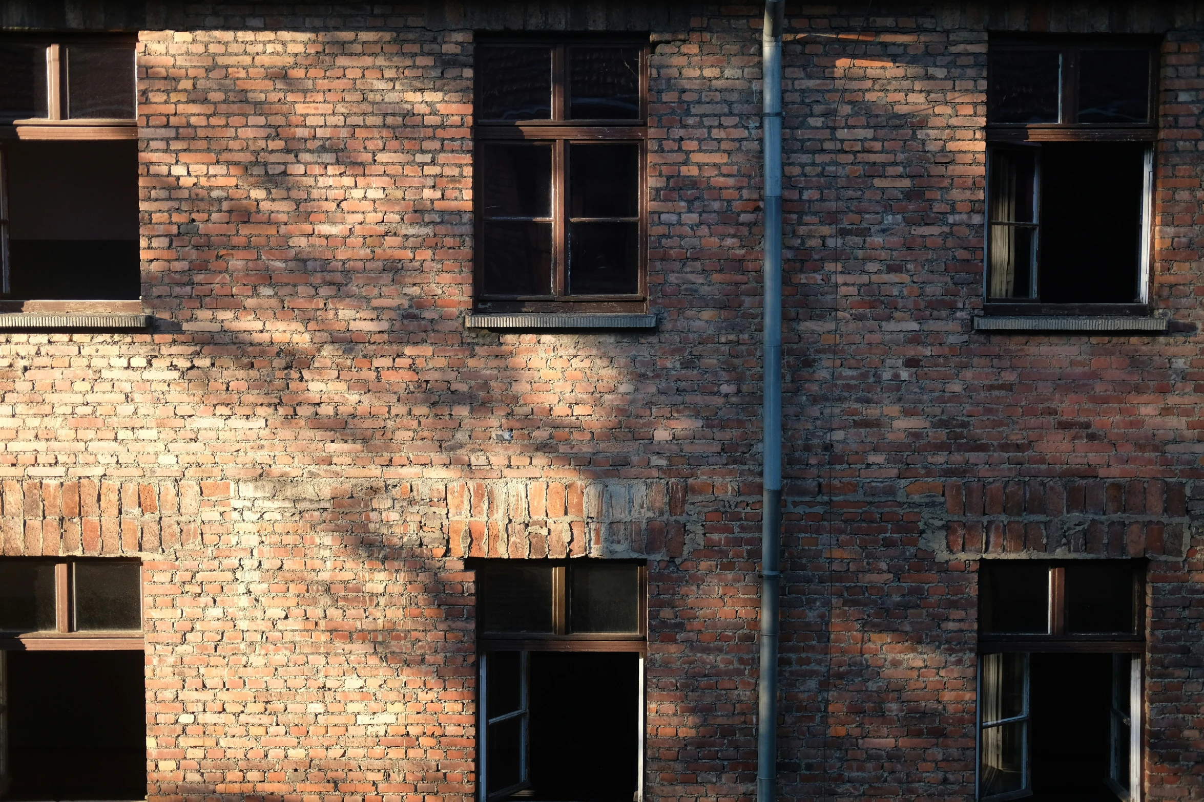 a red brick building with windows and a bench under a tree