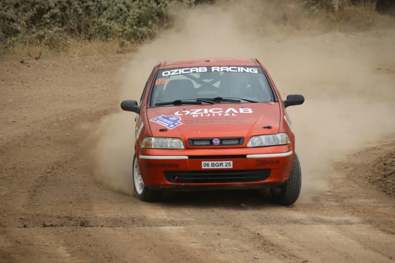 a small car driving on a dirt road near brush