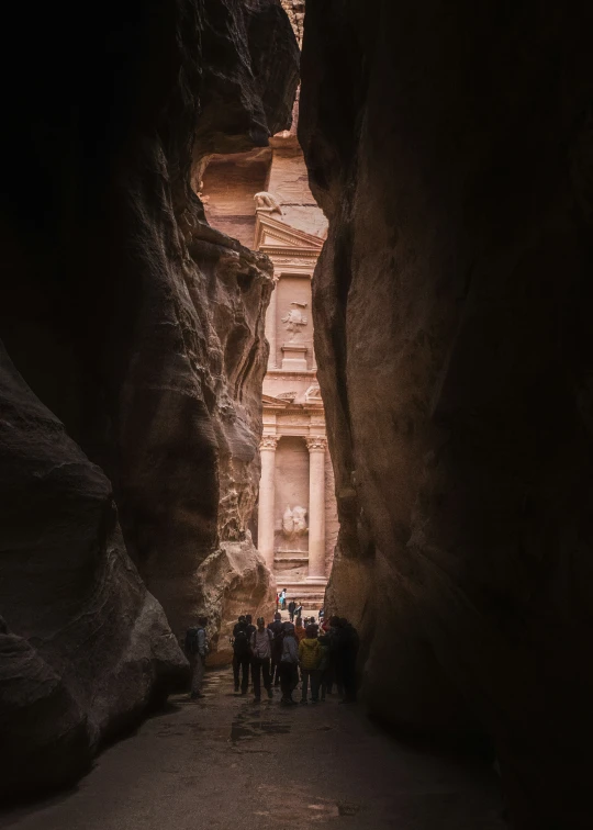 tourists walk through an arch in the narrow alley between the ruins of ancient egypt