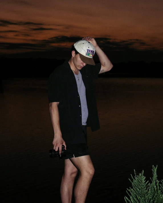 a boy standing with his hands on his hips in front of a body of water