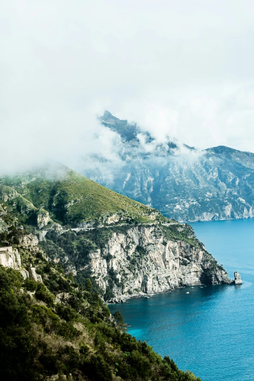 a mountain near the ocean covered with mist